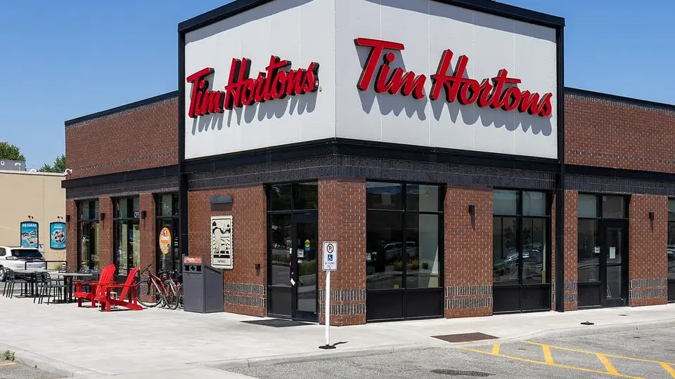 A Tim Hortons restaurant with red patio chairs and a drive-thru lane in Kingsville, Ontario